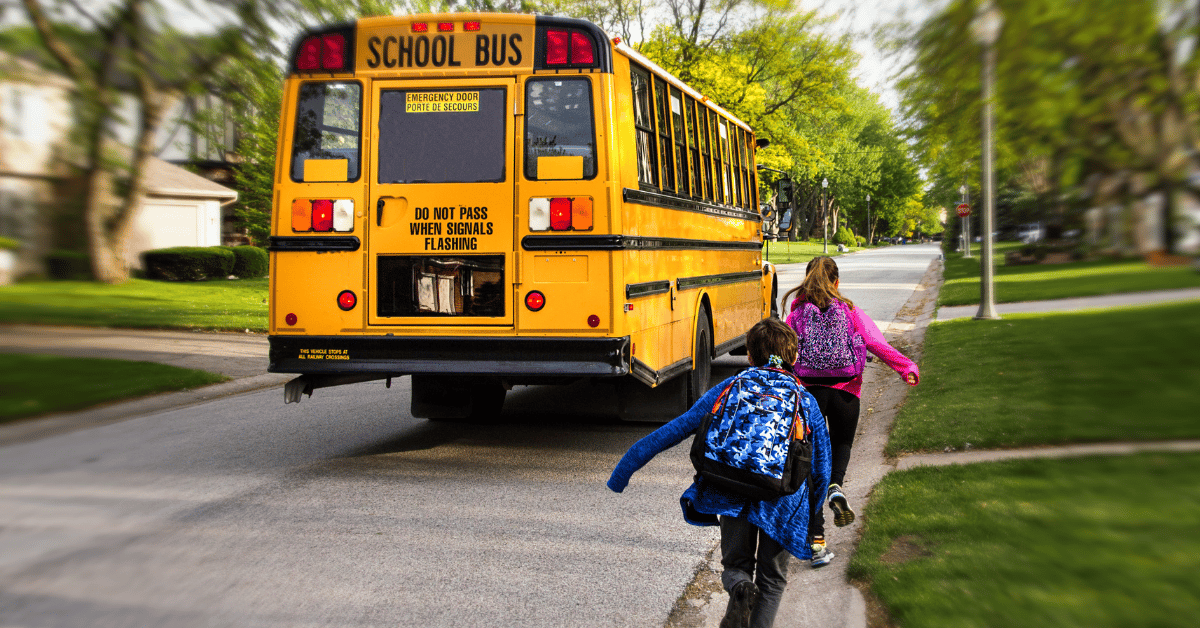 Two kids running to catch school bus.